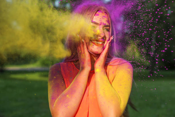 istock Cool young woman posing with exploding yellow paint at summer Holi festival 1328117035