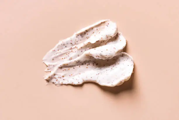 Sample of natural scrub on nude pink background. Peeling cream with microcapsules. Peach or coffee scrub smear.