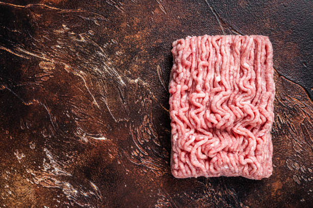 istock Raw ground chicken or turkey meat on brown table. Dark background. Top View. Copy space 1328121660