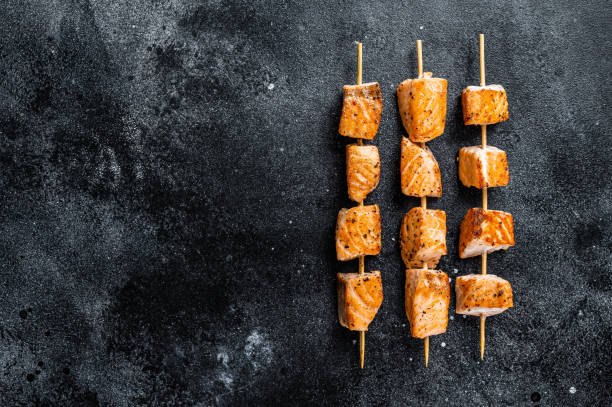 istock Grilled salmon kebab skewers. Black background. Top View. Copy space 1328122570