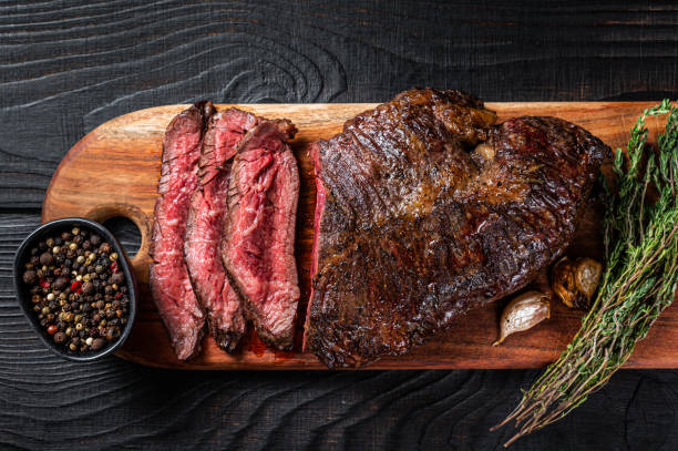 asado carniceros elección bistec onglet colgando carne de ternera tierna en una tabla de cortar. fondo de madera negra. vista superior - roast beef fotos fotografías e imágenes de stock