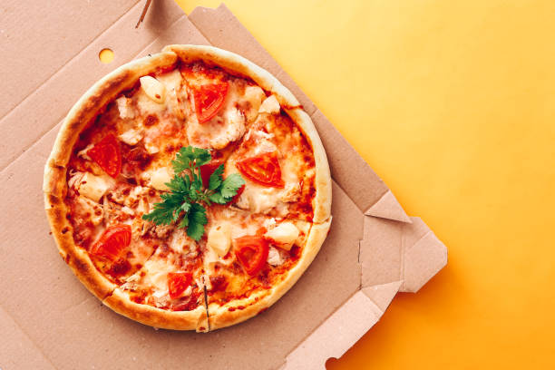 istock Tasty pizza in delivery box on yellow background 1328126717