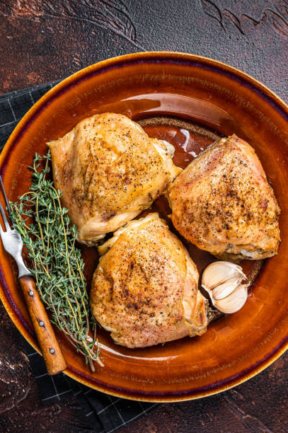istock Roasted chicken thighs with spices in a plate. Dark background. Top View 1328127331