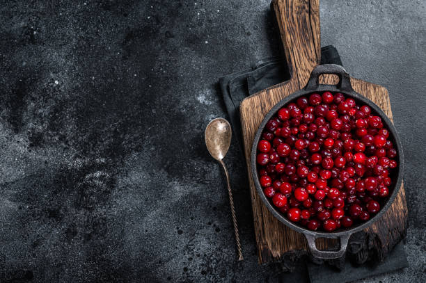 istock Red fresh Cranberry berry in a pan. Black background. Top view. Copy space 1328127433