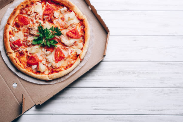 istock Tasty pizza in delivery box on white wooden background 1328127467