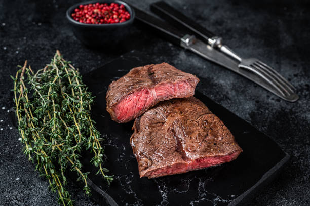 Grilled Top Blade or flat iron roast beef meat steaks on marble board. Black background. Top View Grilled Top Blade or flat iron roast beef meat steaks on marble board. Black background. Top View. blade roast stock pictures, royalty-free photos & images