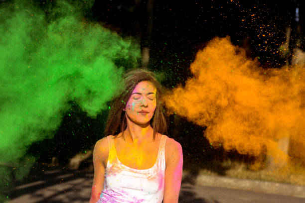istock Beautiful young woman with short hair posing with exploding green and orange Holi paint 1328131734