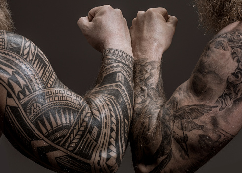 Two viking warrior brother's tattooed arms in studio shot