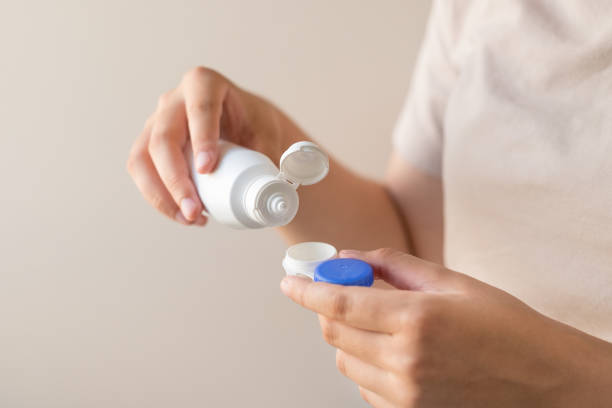 istock Women's hands with a solution and a container for contact lenses. 1328137996