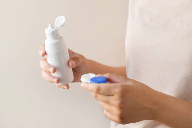 istock Women's hands with a solution and a container for contact lenses. 1328137997