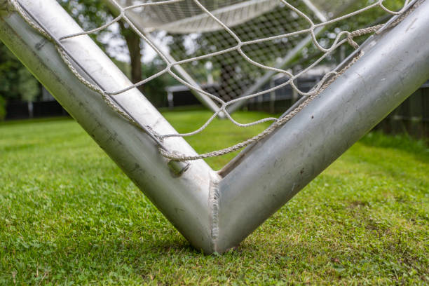 サッカーのゴールの角のクローズアップ。銀鋼と白ネット - soccer man made material goal post grass ストックフォトと画像