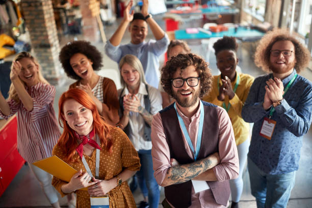 istock Group of young creative people at work is clapping and yelling while posing for a photo in the office together 1328142440