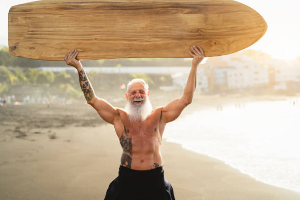istock Senior male having fun surfing during sunset time - Fit retired man training with surfboard on the beach - Elderly healthy people lifestyle and extreme sport concept 1328142497