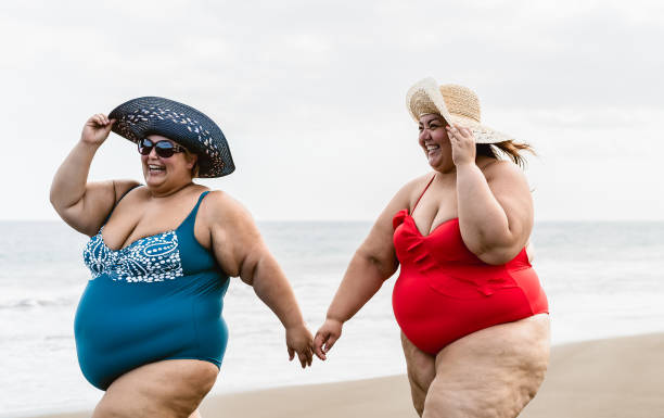 istock Happy plus size women having fun walking on the beach during summer vacations - Overweight people lifestyle concept 1328142568