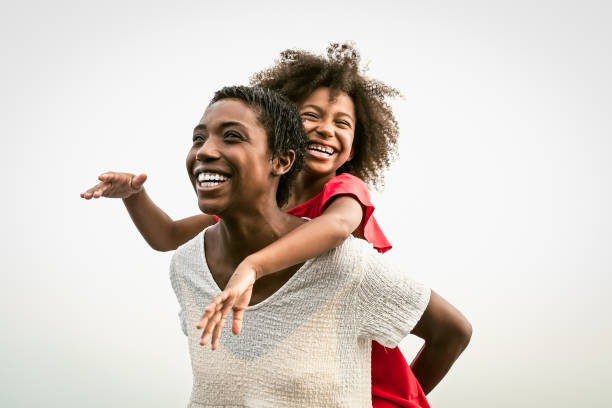 glückliche afrikanische familie am strand in den sommerferien - afro-leute haben spaß im urlaub - eltern lieben und reisen lifestyle-konzept - playful mother playing daughter stock-fotos und bilder