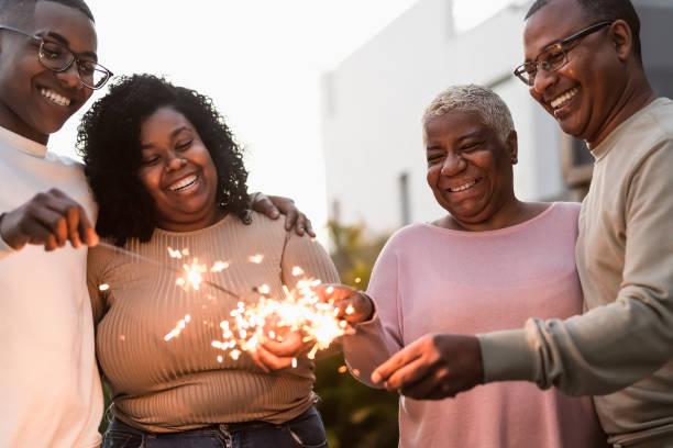 happy african family celebrating with sparklers fireworks at house party - parents unity and holidays concept - latin american and hispanic ethnicity senior adult mature adult couple imagens e fotografias de stock