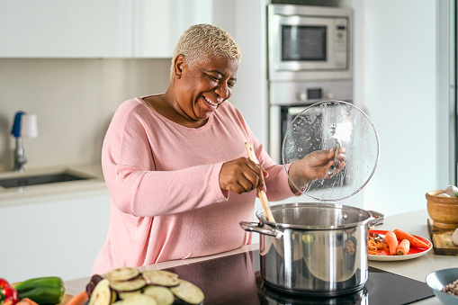 Feliz mujer mayor preparando el almuerzo en la cocina moderna - Madre hispana cocinando para la familia en casa photo