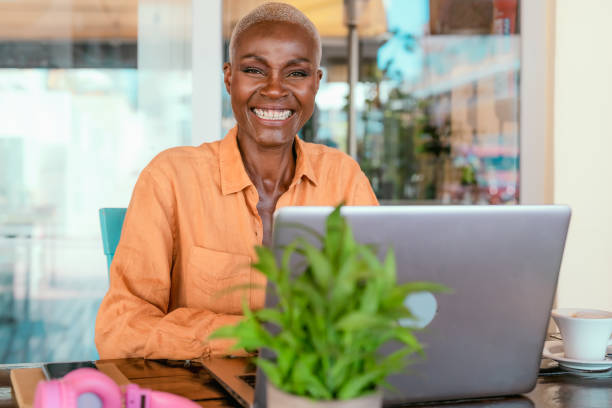 happy african woman working online using laptop in bar restaurant - digital nomad and freelance lifestyle concept - minority professional occupation business ethnic imagens e fotografias de stock