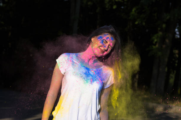 istock Happy brunette woman posing with exploding Holi powder in the park 1328144059