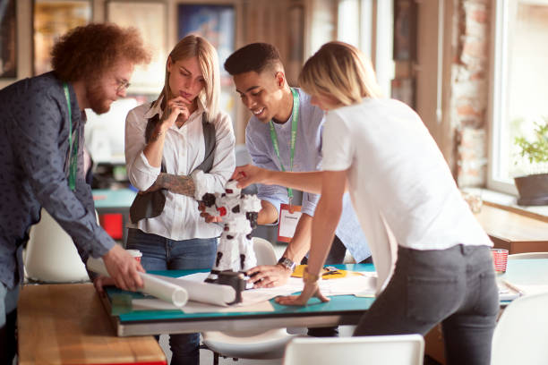istock Group of young creative people is analyzing a robot toy at work in the office 1328144611
