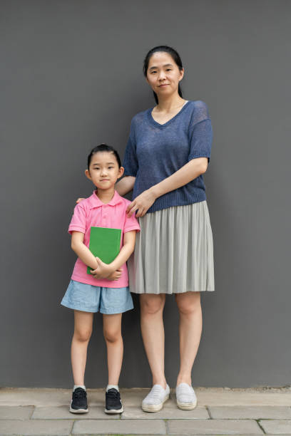 Mother and Daughter Standing on Gray Background