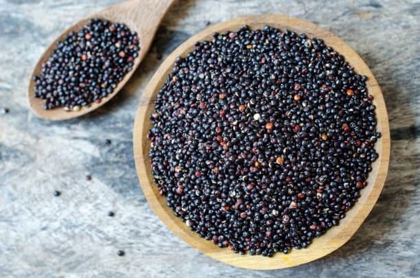 vista superior de las semillas de quinua negra orgánica seca en cuenco de madera y cuchara sobre fondo grunge. concepto de ingrediente alimentario saludable o concepto de producto agrícola - quinoa spoon wood photography fotografías e imágenes de stock