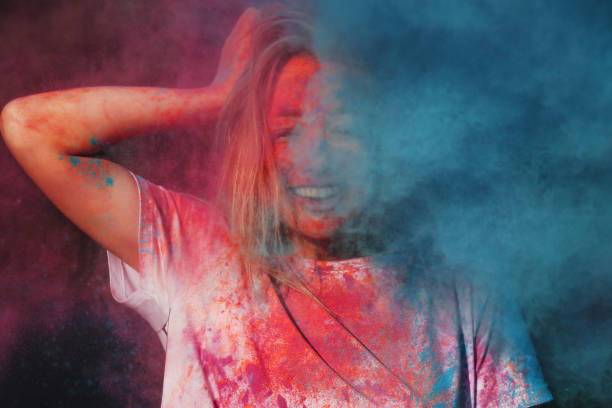 istock Merry blonde woman having fun with exploding blue and pink dry powder celebrating Holi festival 1328149131