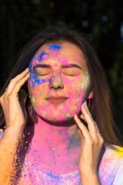 istock Stunning brunette woman posing with exploding blue and yellow Gulal powder in the park 1328149825