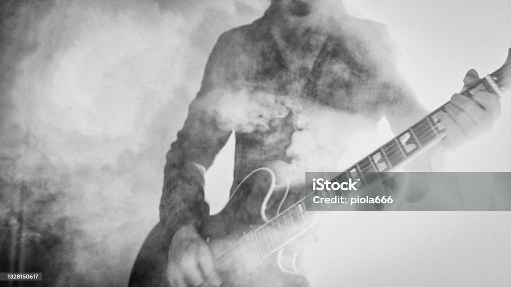 Rock guitarist playing guitar in a live show with stage lights Rock guitarist playing guitar in a live show, lights and smoke Rock Music Stock Photo