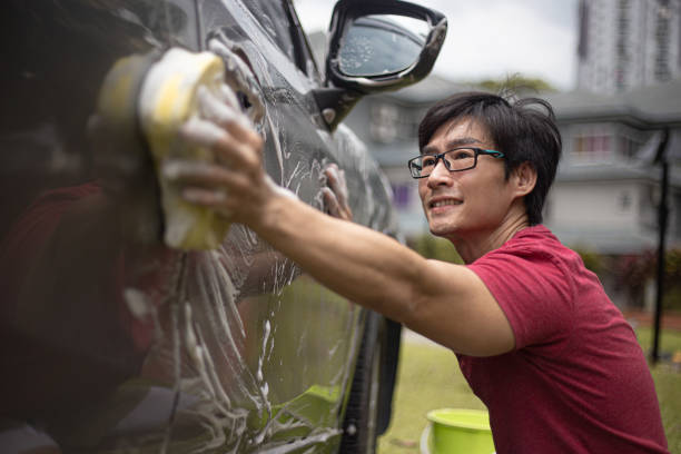 Asian Chinese mid adult man washing car at his backyard stock photo