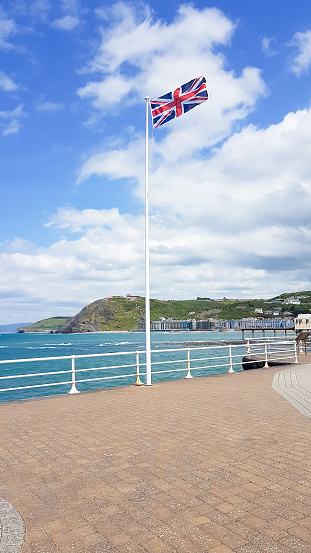 The university town of Aberystwyth with Union jack flying on the promenade and the sea looking blue on a sunny summers day.
