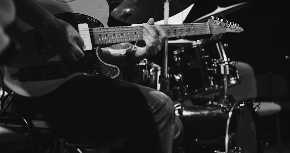 Black and white image. Repetition of rock music band at music studio. Cropped image of electric and acoustic guitar players at concert. Rehearsal base Concept of art, music, style. Out of focus effect