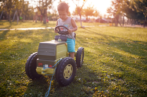 caucasian toddler enjoying ride on his plastic tractor toy