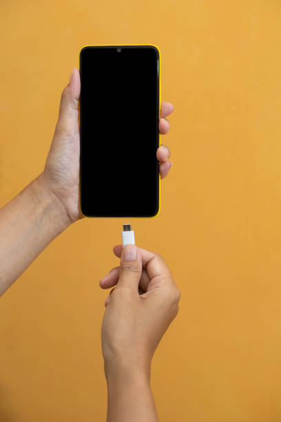 istock woman's hand plugs micro usb cable into blank black screen smartphone to charge battery 1328155324