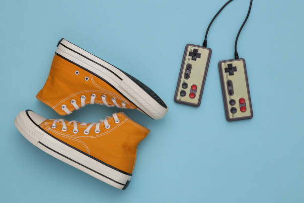 istock Retro sneakers (gumshoes) with retro joysticks on blue background. Top view. 80s. Flat lay 1328156445