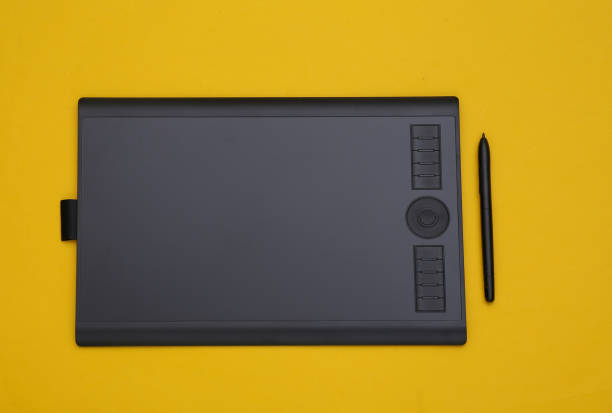 Graphic tablet with pen on yellow background. Top view