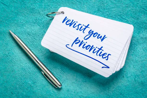 revisit your priorities advice - handwriting on a stack of index cards, business, productivity and lifestyle concept