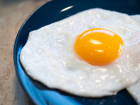 Perfect fried egg with uncooked yolk on blue dish