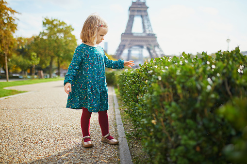 Adorable toddler girl walking near the Eiffel tower in Paris, France. Happy child enjoying fall day. Outdoor autumn activities for kids