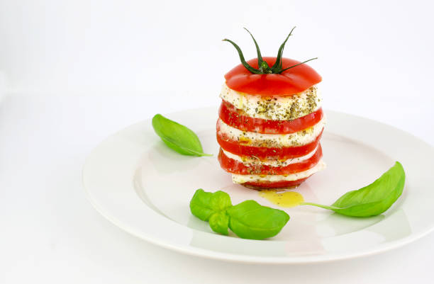 Delicious caprese salad with ripe tomatoes and mozzarella cheese with fresh basil leaves. White background.