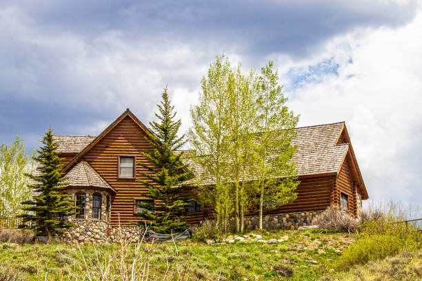 Luxury log cabin with wooden roof and rock bay window on hilltop surrounded by pines and quaking aspens Luxury log cabin with wooden roof and rock bay window on hilltop surrounded by pines and quaking aspens aspen colorado photos stock pictures, royalty-free photos & images
