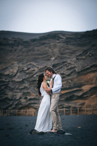 istock Newlyweds dance on rocky beach after wedding 1328182848