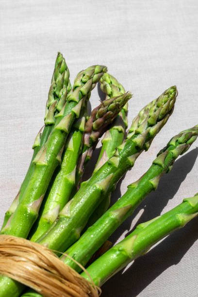 istock Fresh green asparagus vegetables bunch on beige fabric linen textile background closeup. Healthy diet concept. 1328183355