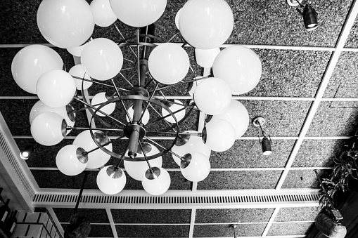Ceiling lamp with white glass balls in a bar. Monochrome picture.