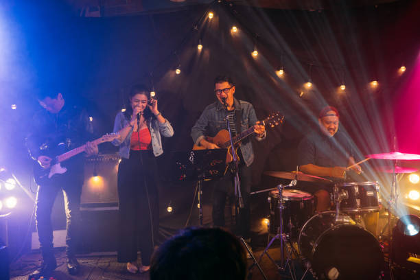 Musicians in concert. Males playing guitar or drum and female singing on a stage at night on weekend, Live music concept. string ensemble stock pictures, royalty-free photos & images