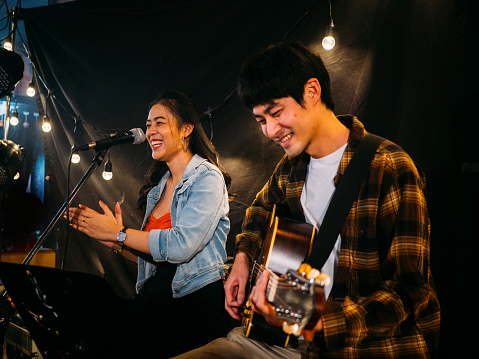 Asian woman singing and man playing the guitar live music on stage.