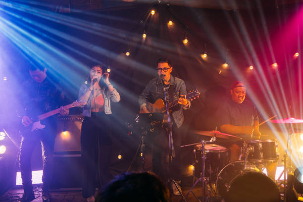 In concert. Music band performing on stage at the concert, having a singer singing song and team playing musical instruments in the club. string ensemble stock pictures, royalty-free photos & images