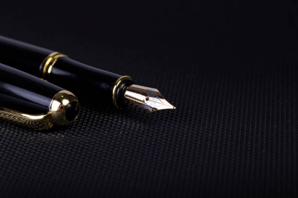 istock Black fountain pen on a black plastic desk 1328197408