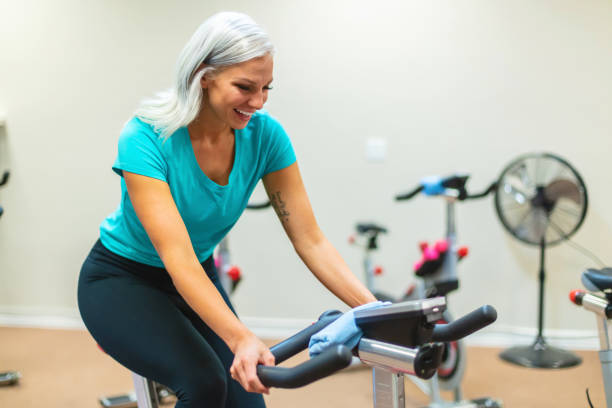 istock Millennial Female Working Out in Gym Setting Using Weights on Stationary Fitness Spin Cycle Photo Series 1328197621