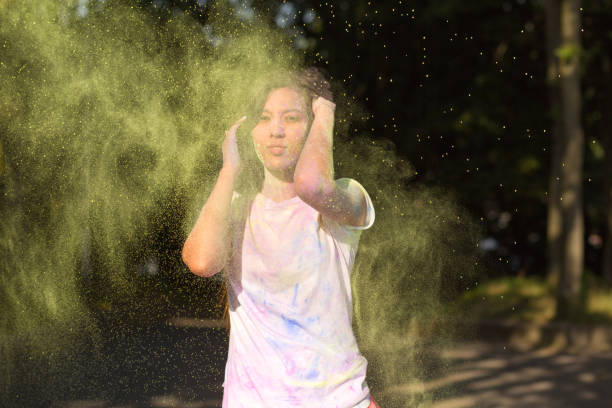 istock Glorious brunette asian woman with long hair playing with Holi paint exploding around her 1328198533